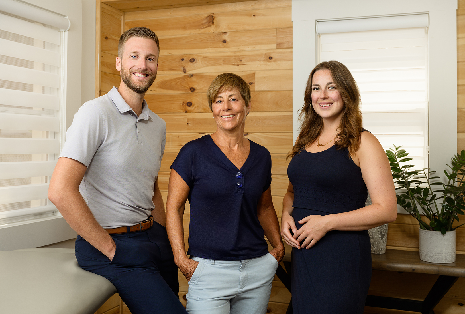 The osteopathy team standing in front of a wooden wall.